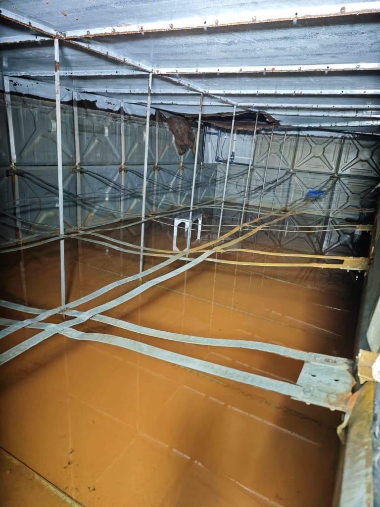 Modüler su deposu içinde biriken kirli ve tortulu su – temizlik ve bakım gerektiren depo iç görüntüsü.